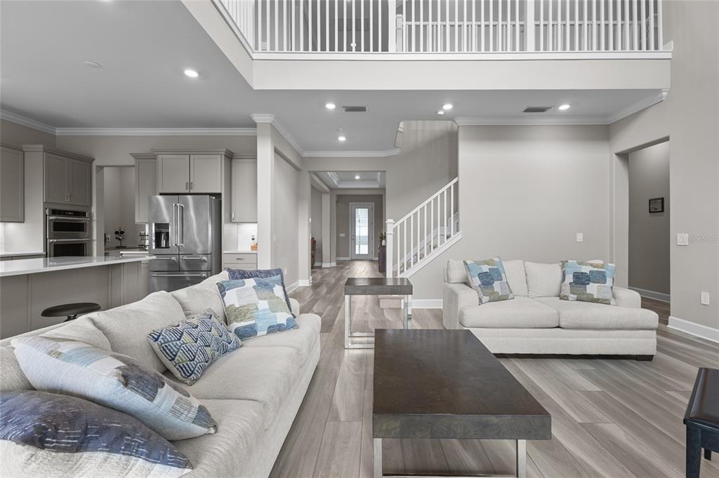 A living room with light wood floors, a white sofa, and a staircase — 5855 SILVERSIDE PINE COURT, LAKEWOOD RANCH, FL