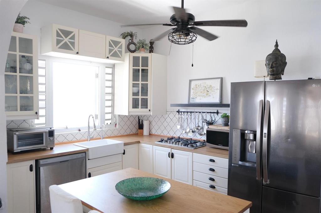 A kitchen features white cabinets, a farmhouse sink, a wooden island, and a stainless refrigerator — 200 SOL ST. UNIT PH-D1, OLD SAN JUAN, PR