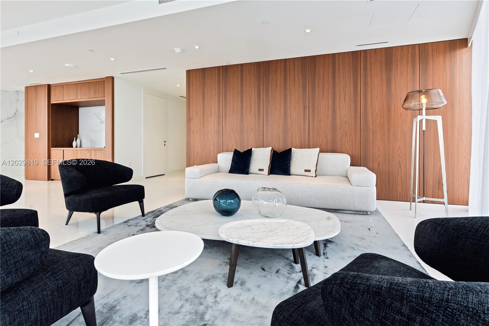 A modern living room features a white sofa, black armchairs, and wood-paneled walls — 300 E Biscayne Blvd Way # 5101, Miami FL 33131, MIAMI, FL