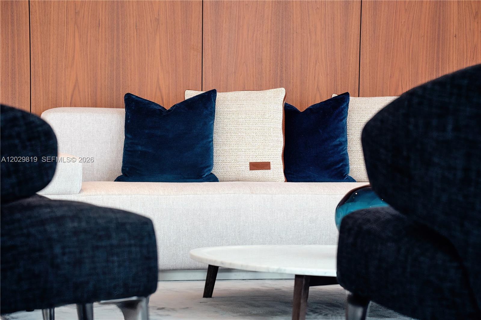 A light-colored sofa with blue and textured pillows sits in front of wood paneling — 300 E Biscayne Blvd Way # 5101, Miami FL 33131, MIAMI, FL