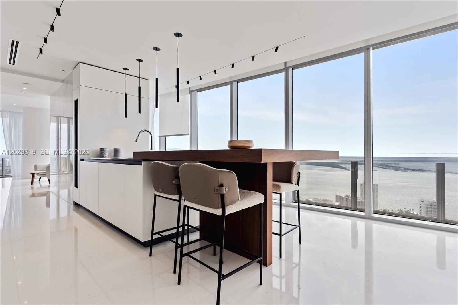 A modern kitchen features a wooden island with bar stools and floor-to-ceiling windows overlooking water — 300 E Biscayne Blvd Way # 5101, Miami FL 33131, MIAMI, FL