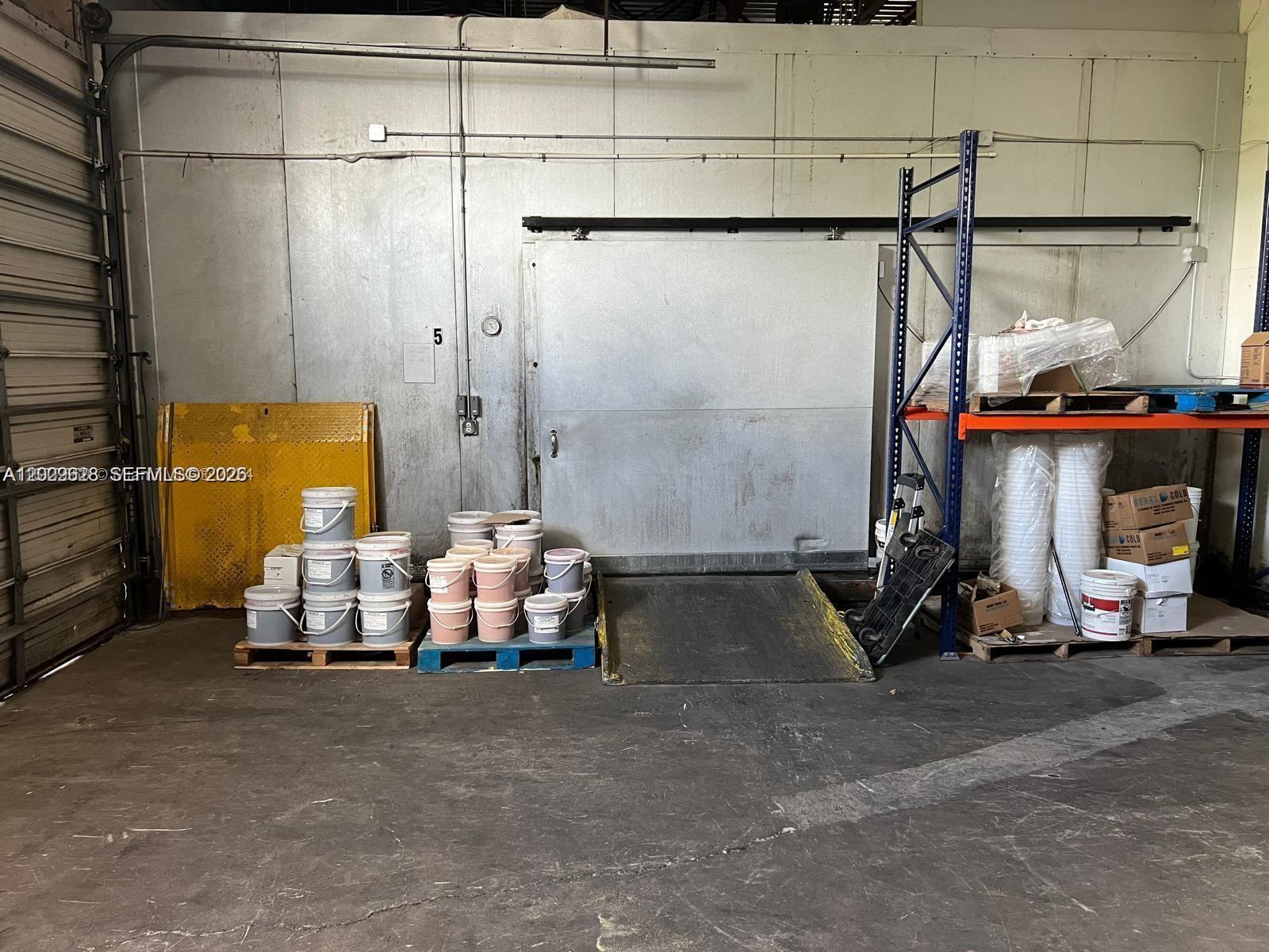 A warehouse interior features a large sliding metal door, storage pallets, and industrial shelving — 1950 Hayes St, Hollywood FL 33020, HOLLYWOOD, FL