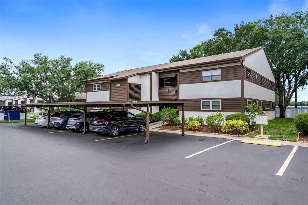 A two-story apartment building with a covered parking area and several parked cars — 4101 PASSPORT LANE UNIT 202, NEW PORT RICHEY, FL