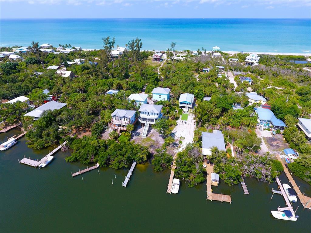 An aerial view shows several houses nestled among trees along a waterfront with private docks — 8146 LITTLE GASPARILLA ISLAND, PLACIDA, FL