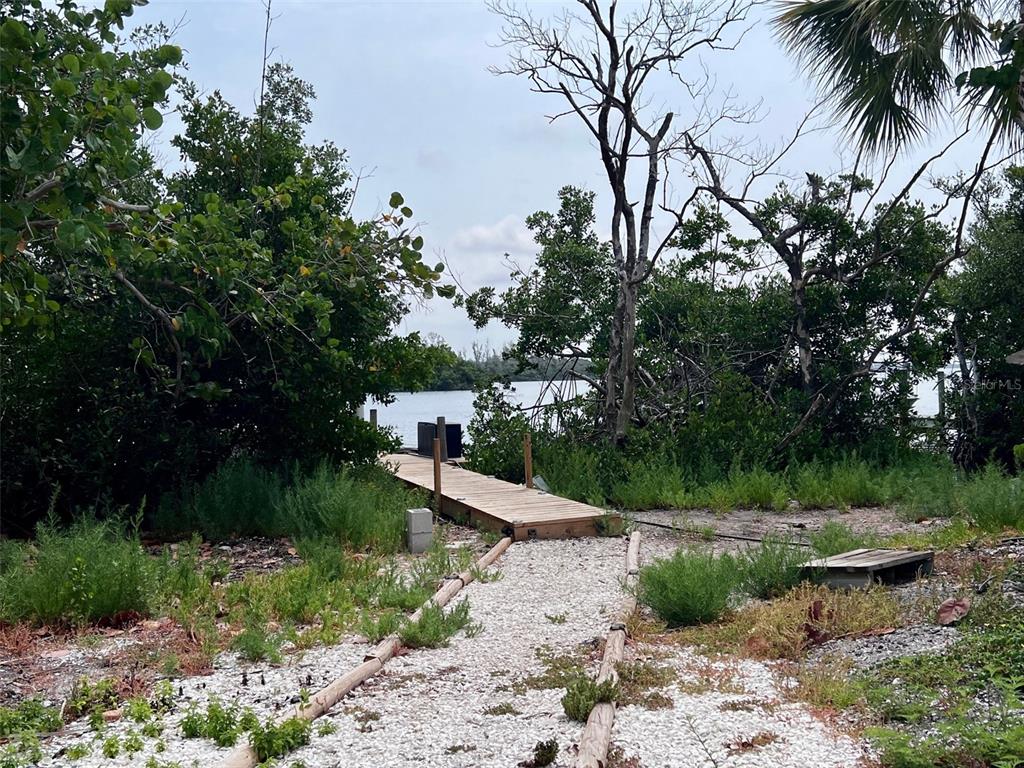 A shell path leads to a wooden dock overlooking a body of water with trees — 8146 LITTLE GASPARILLA ISLAND, PLACIDA, FL