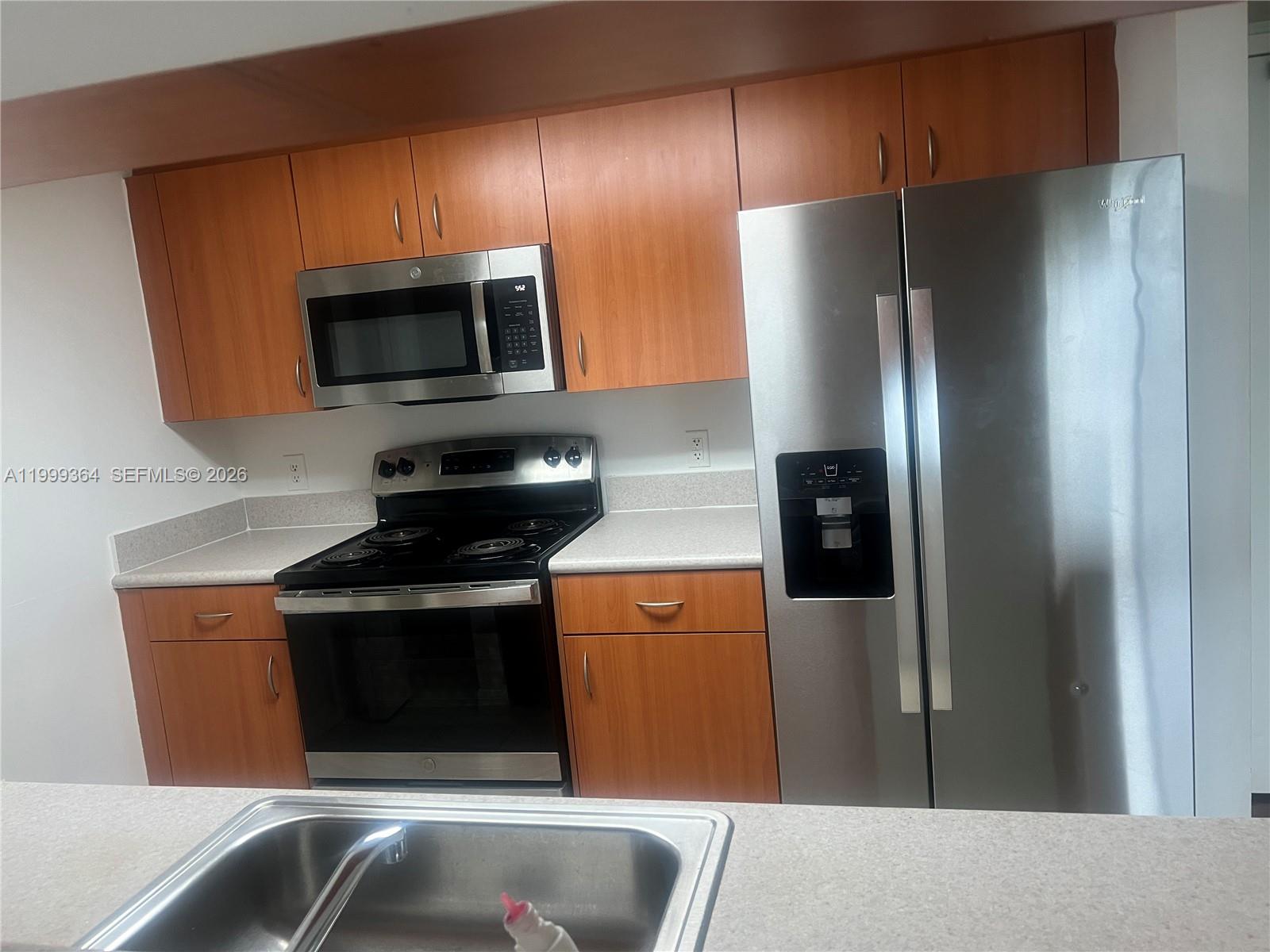 A kitchen features wood cabinets, stainless steel appliances, and light-colored countertops — 816 NW 11th St # 1002, Miami FL 33136, MIAMI, FL