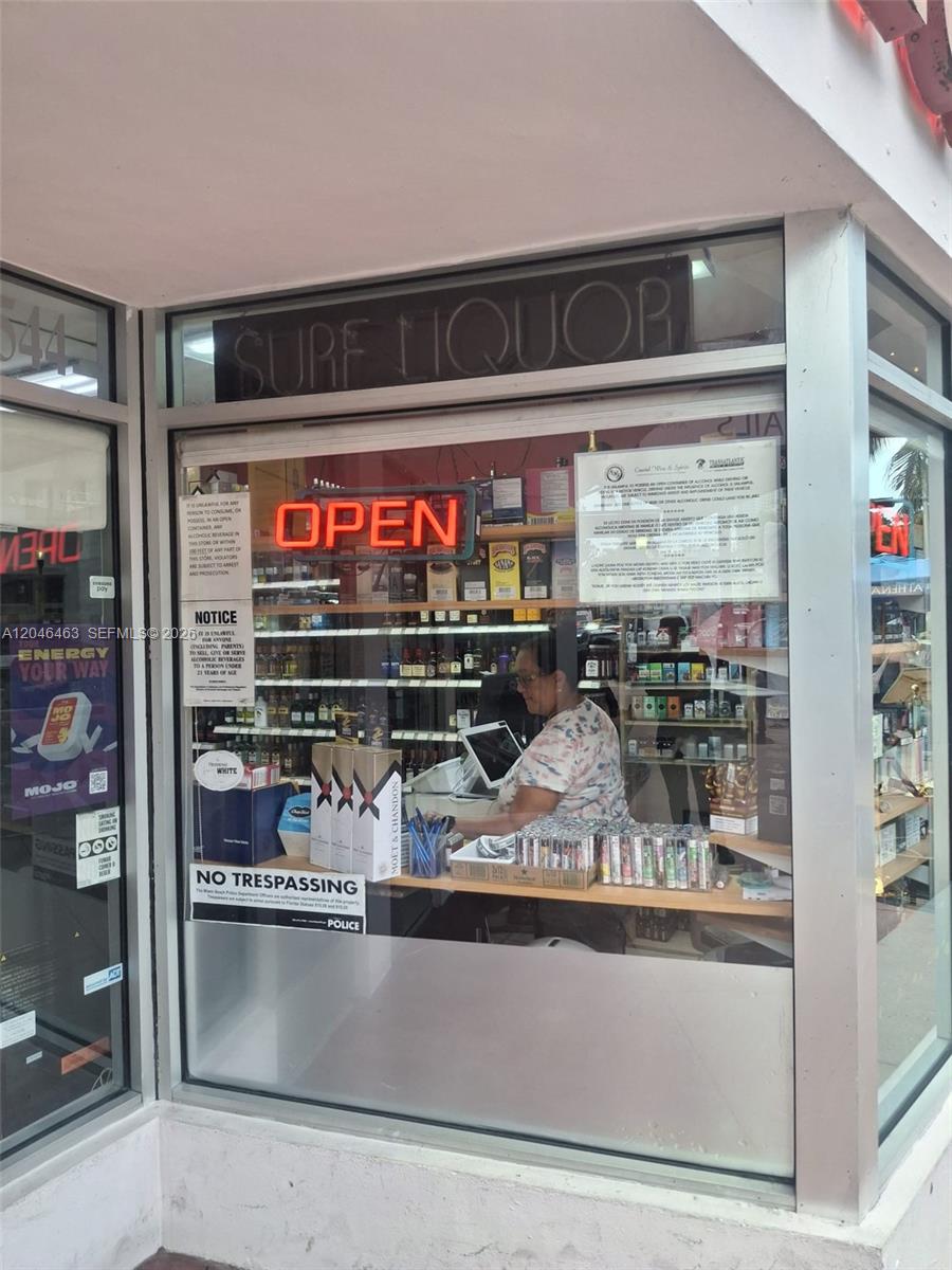 A view through the storefront window of a liquor store with a clerk inside — Washington Ave, Miami Beach FL 33139, MIAMI BEACH, FL