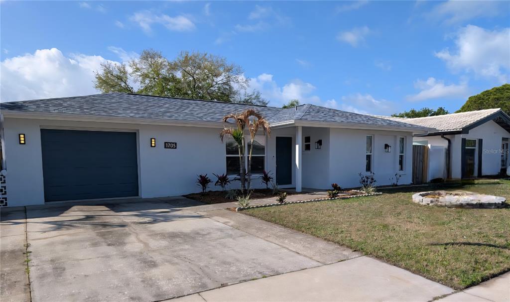 A single-story house with a white exterior, a gray garage door, and a concrete driveway — 1705 IRONWOOD COURT E, OLDSMAR, FL