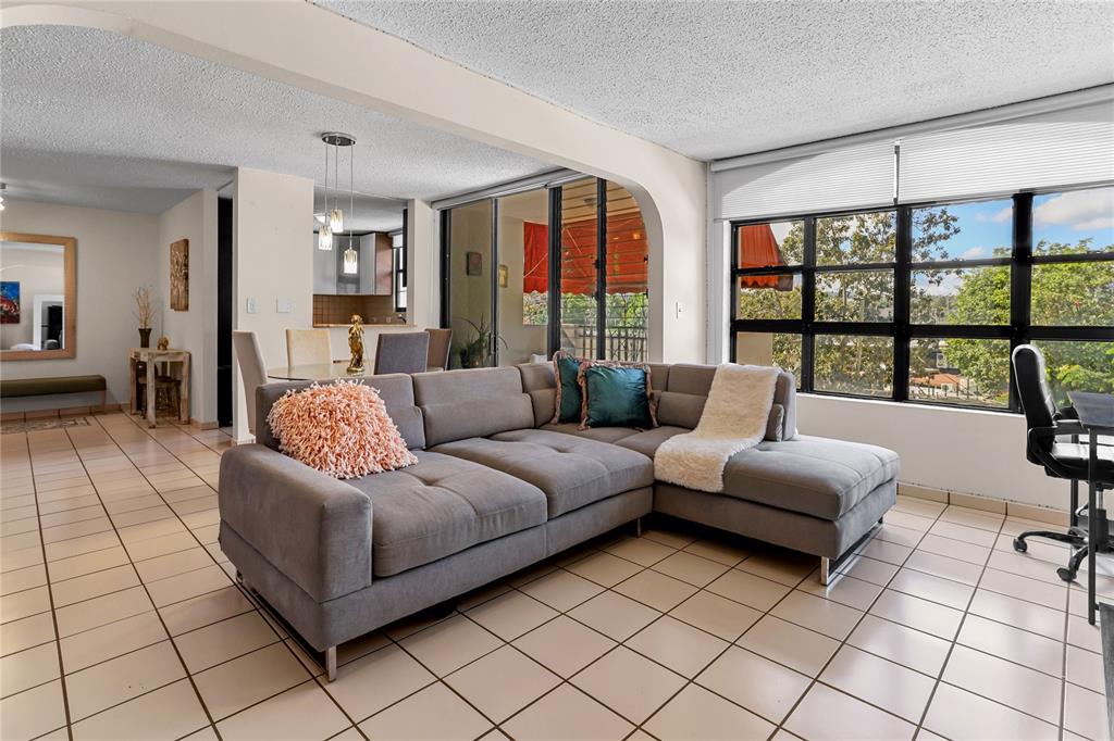 A living room features a grey sectional sofa, tile flooring, and large windows with views — 24a LOPATEGUI UNIT 107a, GUAYNABO, PR
