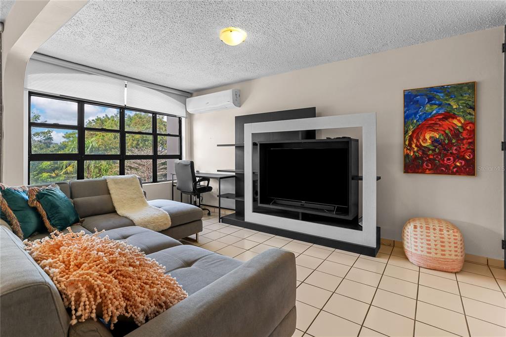 A living room features a gray sectional sofa, a television unit, and tile flooring — 24a LOPATEGUI UNIT 107a, GUAYNABO, PR