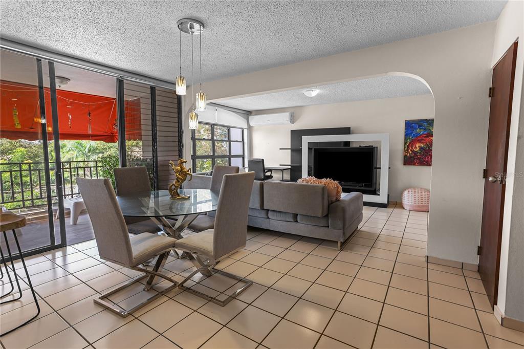 An open-concept living and dining area features tile floors, a glass table, and a balcony — 24a LOPATEGUI UNIT 107a, GUAYNABO, PR