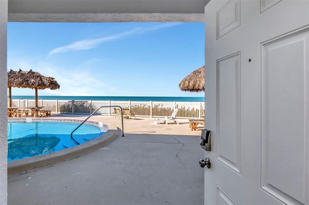 An aerial view shows a beachfront building with a pool and a yellow arrow pointing down — 2700 GULF BOULEVARD UNIT 2W, BELLEAIR BEACH, FL