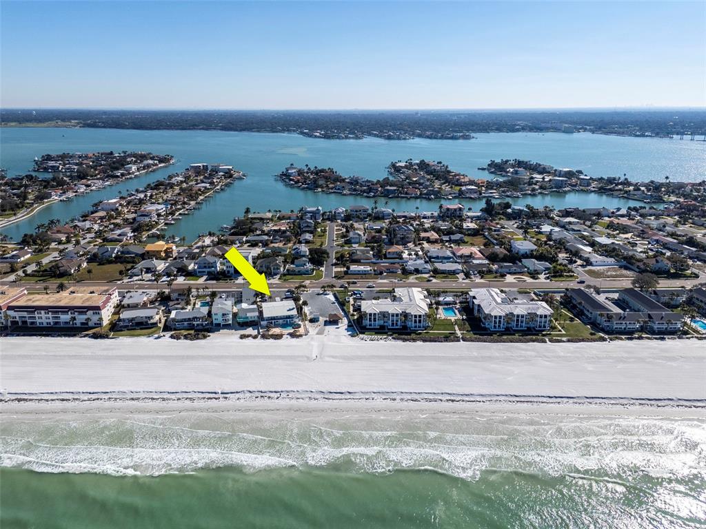 A swimming pool sits in front of a two-story building beside a beach with palm trees — 2700 GULF BOULEVARD UNIT 2W, BELLEAIR BEACH, FL
