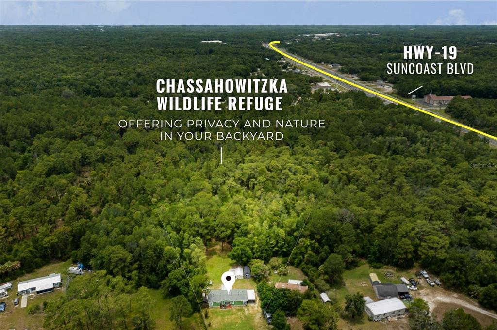 An aerial view shows a house situated next to a large, dense forest area — 7927 W CYPRIAN COURT, HOMOSASSA, FL