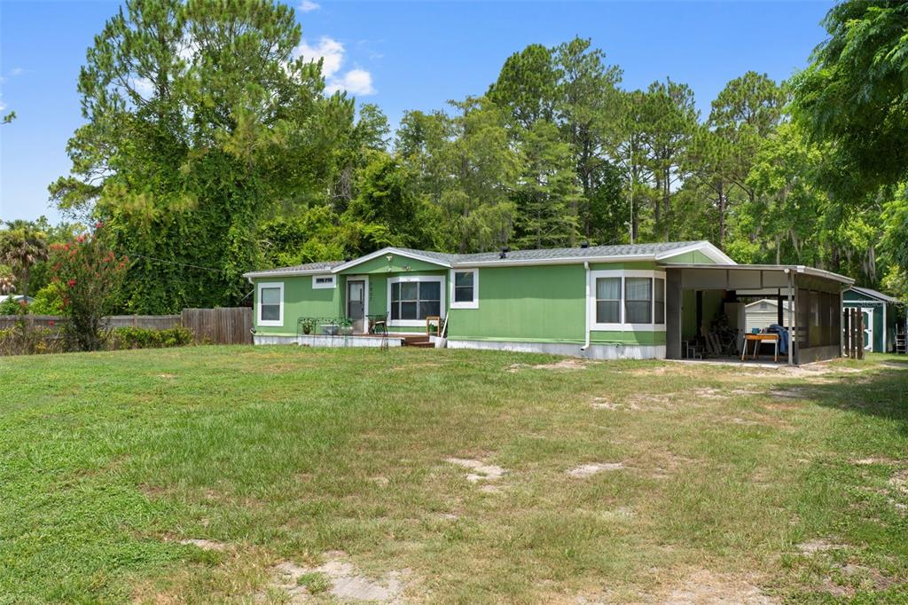 A green single-wide mobile home with a carport sits on a large grassy lot — 7927 W CYPRIAN COURT, HOMOSASSA, FL