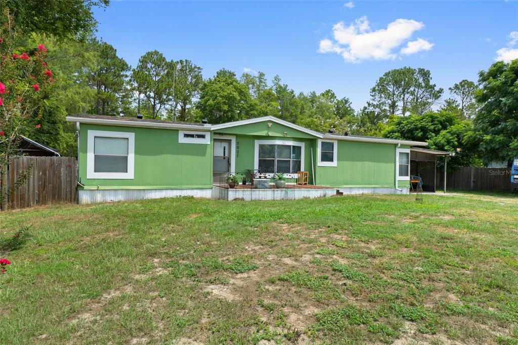 A green single-story manufactured home with a front deck sits on a grassy lot — 7927 W CYPRIAN COURT, HOMOSASSA, FL