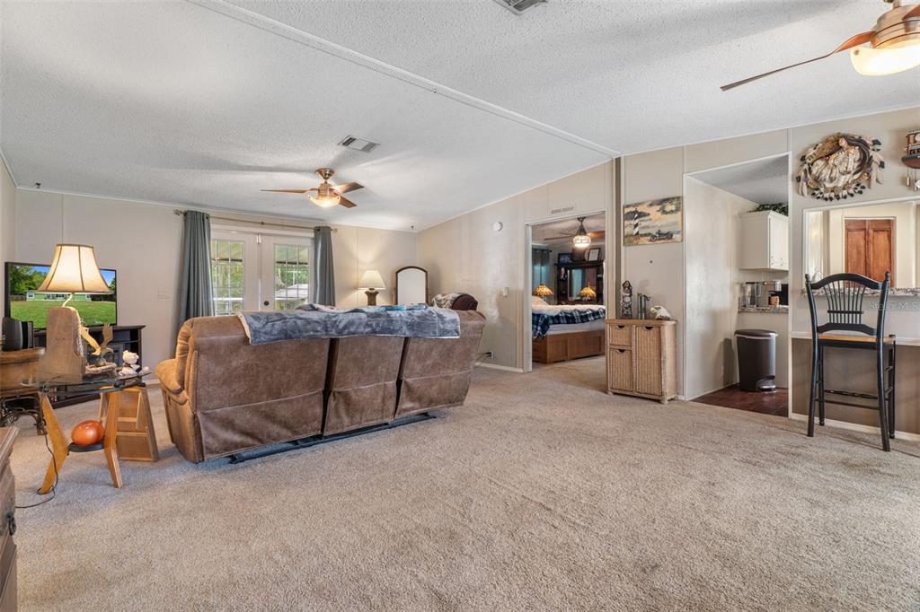A living room with beige carpet, a brown sofa, and a doorway leading to a bedroom — 7927 W CYPRIAN COURT, HOMOSASSA, FL
