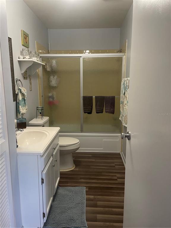 A bathroom features a white vanity, a toilet, and a shower-tub combo with sliding doors — 163 JACKSON STREET, LAKE WALES, FL