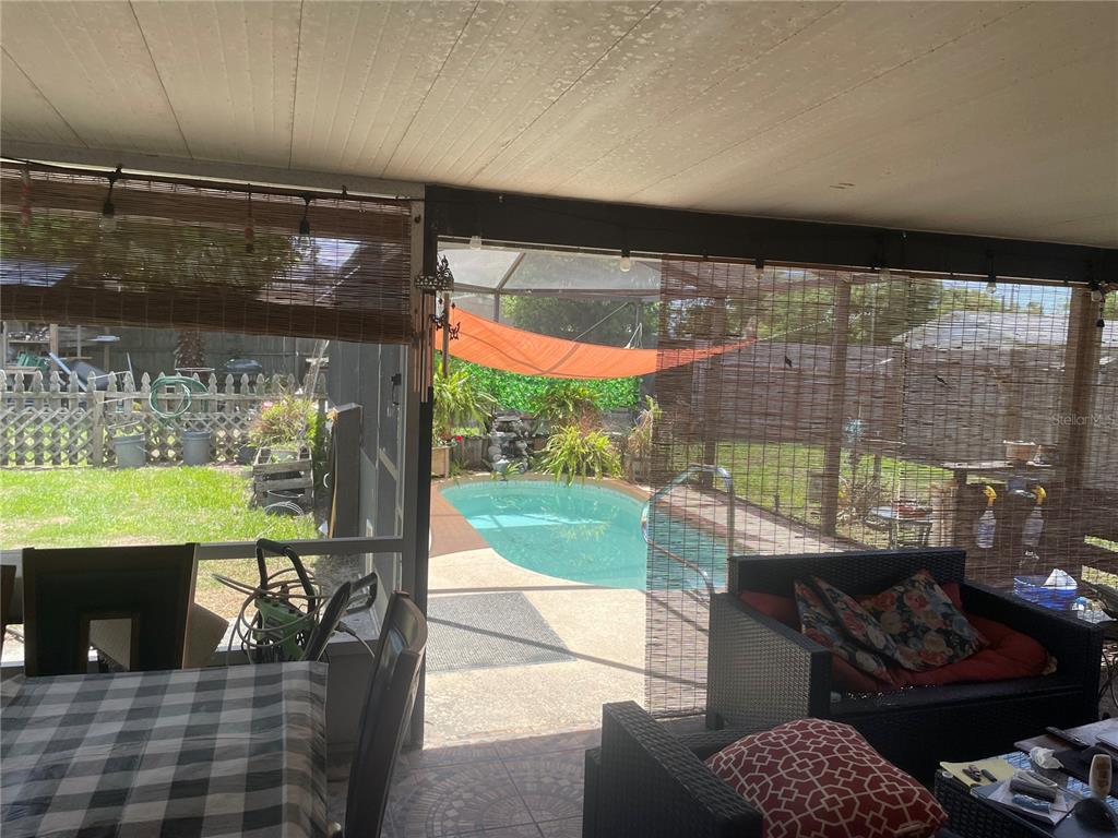 A covered patio overlooks a backyard swimming pool enclosed by a screen — 163 JACKSON STREET, LAKE WALES, FL