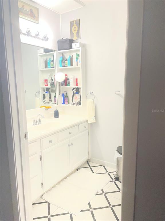 A bathroom features a white vanity, a mirrored medicine cabinet, and black-and-white tiled flooring — 163 JACKSON STREET, LAKE WALES, FL