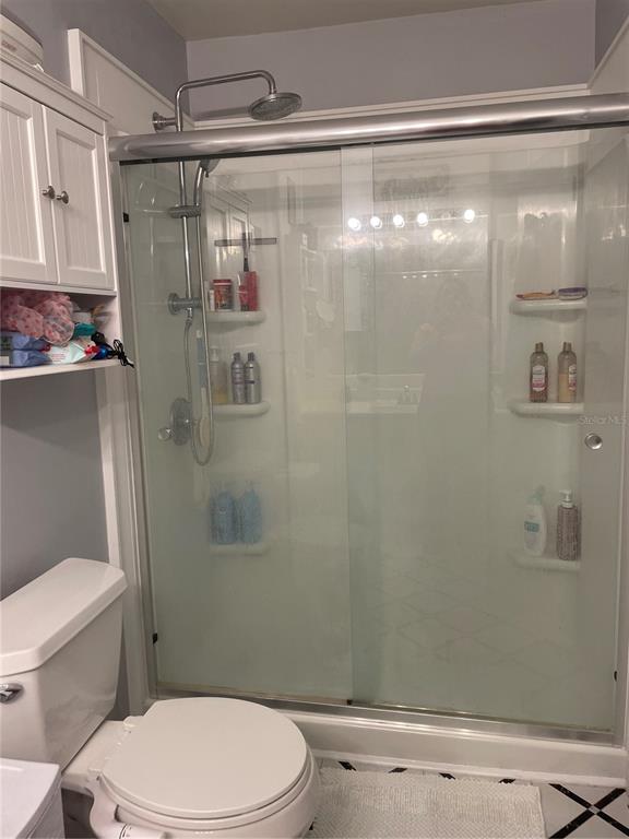 A bathroom features a white toilet next to a glass-enclosed shower with built-in shelving — 163 JACKSON STREET, LAKE WALES, FL