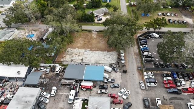 An aerial view shows a vacant dirt lot surrounded by commercial buildings and parking areas — 9330 1ST AVENUE, ORLANDO, FL