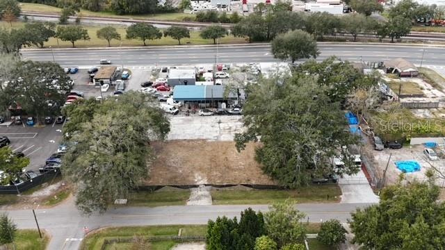 An aerial view shows a vacant rectangular lot surrounded by trees, parking areas, and roads — 9330 1ST AVENUE, ORLANDO, FL