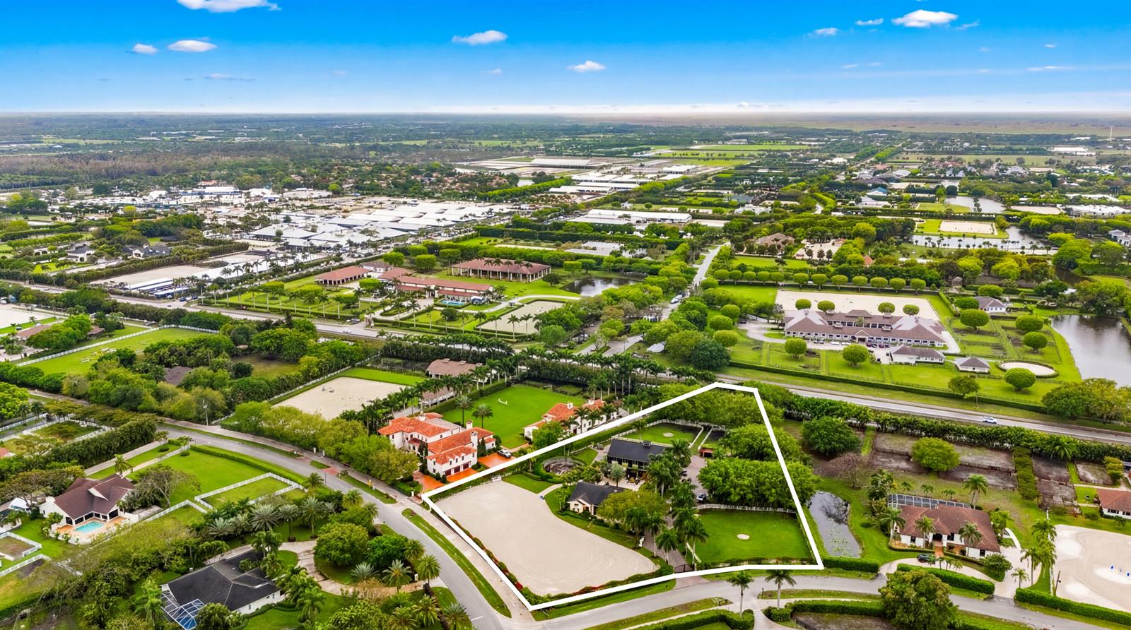 An aerial view shows a residential property with a riding arena, stables, and lush landscaping — 14911 Equestrian Way, Wellington FL 33414, WELLINGTON, FL