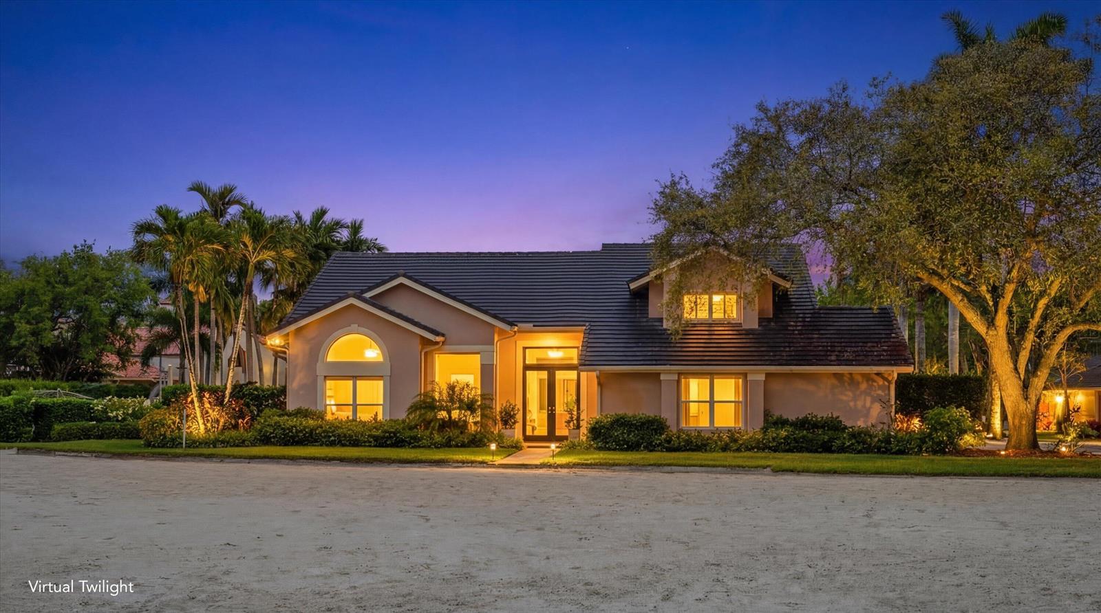A single-story house with a dark tile roof and illuminated windows at twilight — 14911 Equestrian Way, Wellington FL 33414, WELLINGTON, FL