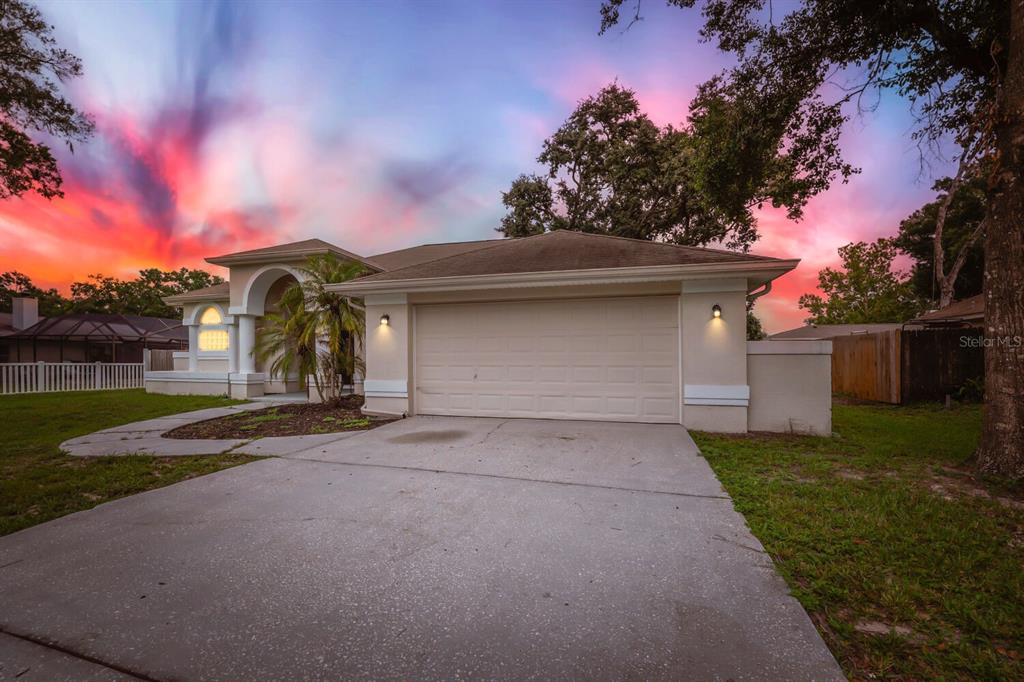 A single-story house with a beige stucco exterior, a two-car garage, and a concrete driveway — 4924 CANTERBURY DRIVE, LAND O LAKES, FL