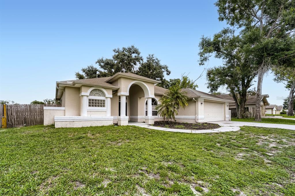 A single-story beige stucco house with an arched entryway and a two-car garage — 4924 CANTERBURY DRIVE, LAND O LAKES, FL