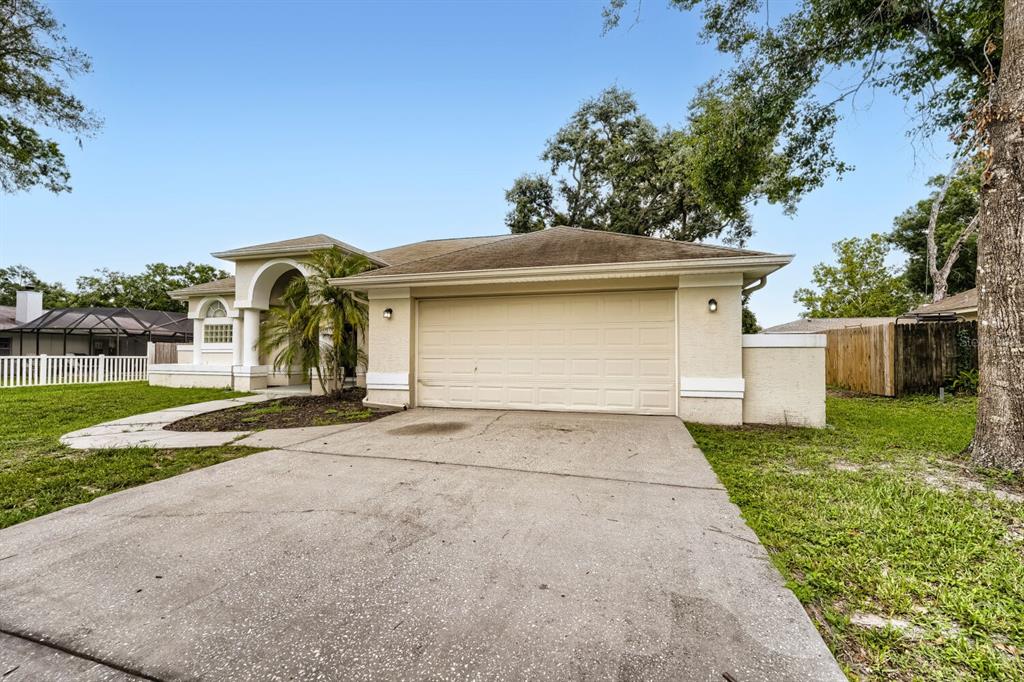 A single-story house with a beige stucco exterior, a two-car garage, and a concrete driveway — 4924 CANTERBURY DRIVE, LAND O LAKES, FL