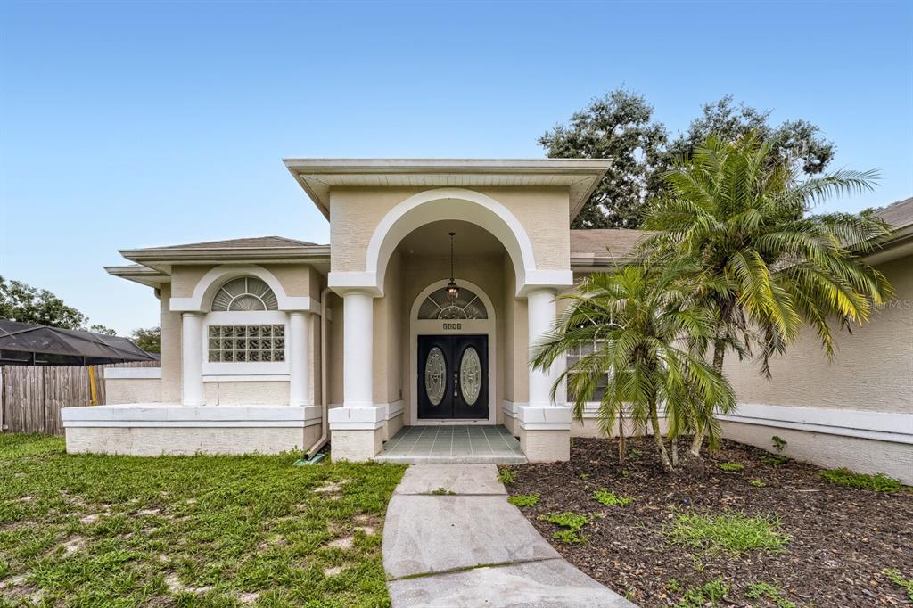 The exterior of a single-story house features a covered entryway with columns and double doors — 4924 CANTERBURY DRIVE, LAND O LAKES, FL