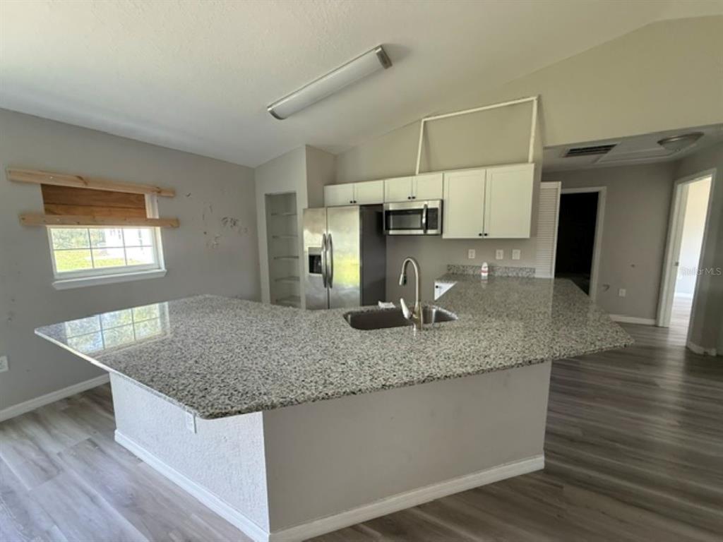 A kitchen features a large granite island, stainless steel appliances, and white upper cabinets — 2 DOGWOOD DRIVE RADL., OCALA, FL