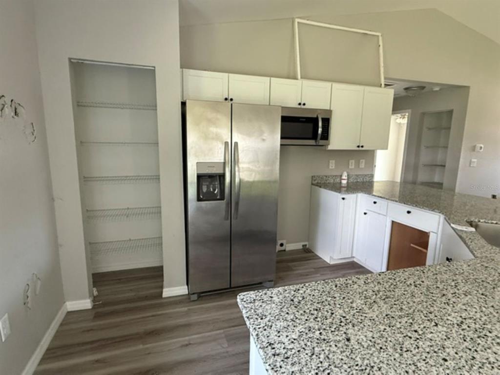 A kitchen features stainless steel appliances, white cabinets, granite countertops, and an open pantry — 2 DOGWOOD DRIVE RADL., OCALA, FL