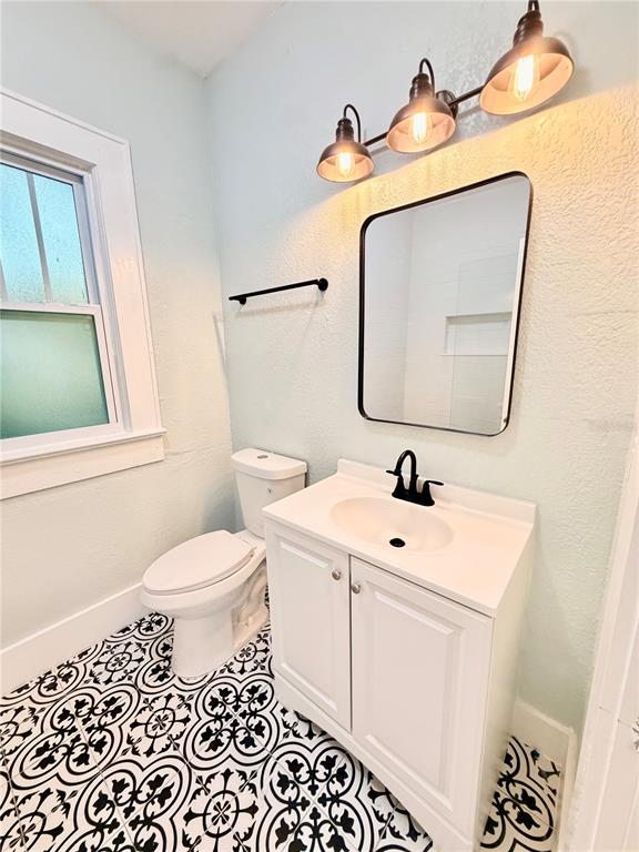 A covered front porch features wood-look decking, blue siding, a white door, and a window — 1200 E HENRY AVENUE, TAMPA, FL