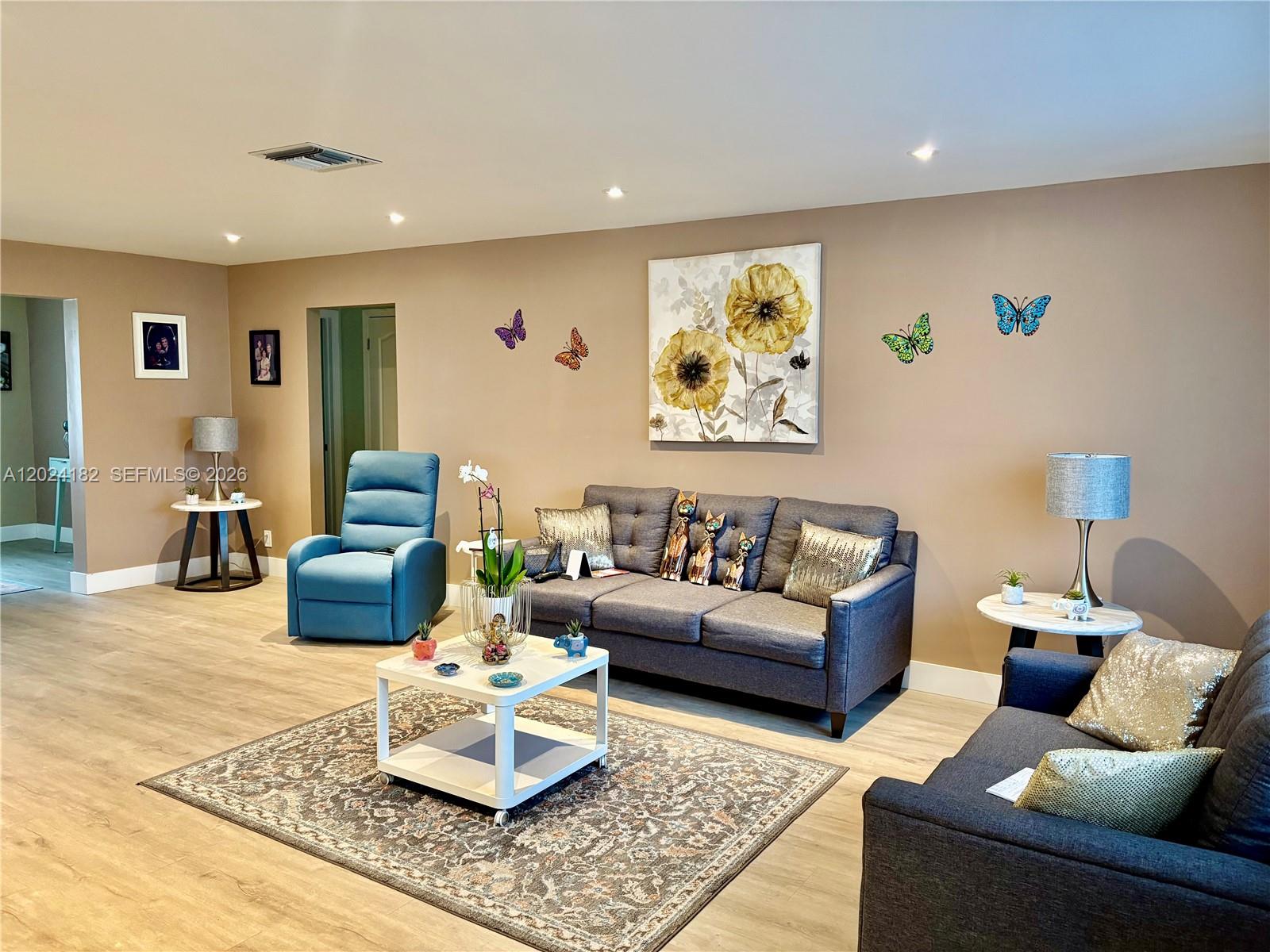 A living room features two gray sofas, a blue recliner, and butterfly wall decor — 8225 NW 12th Ct, Plantation FL 33322, PLANTATION, FL