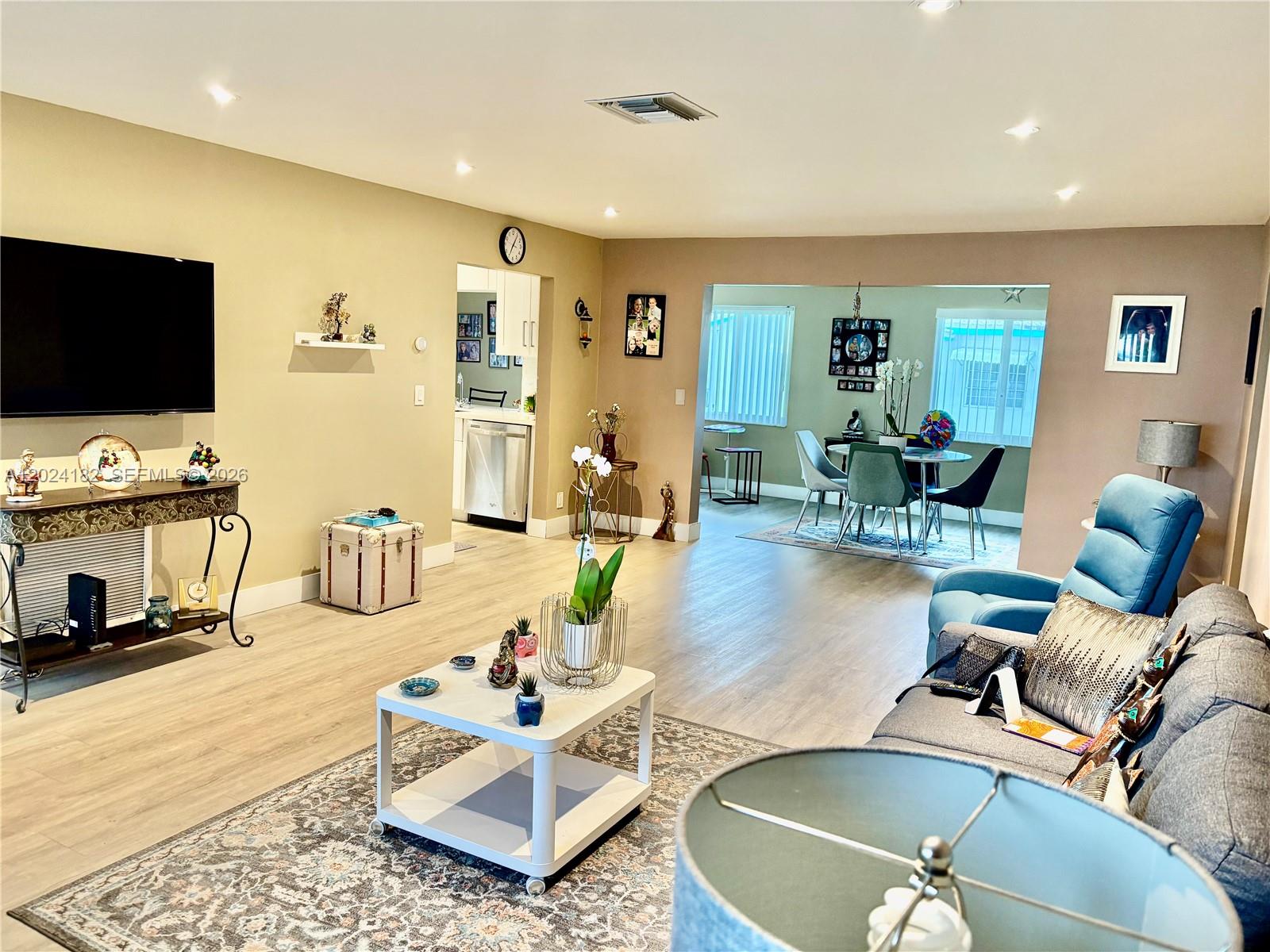 A living room with light wood floors, a gray sofa, and an adjacent dining area — 8225 NW 12th Ct, Plantation FL 33322, PLANTATION, FL