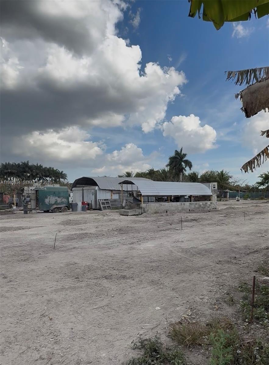 A dirt lot features a metal-roofed structure and a trailer under a cloudy sky — 16455 SW 207, Homestead FL 33187, HOMESTEAD, FL