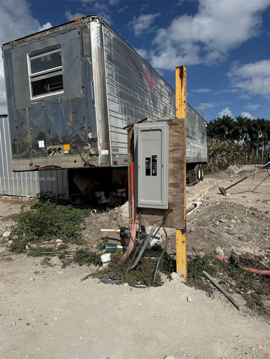 An electrical panel mounted on a wooden post stands in front of a semi-trailer — 16455 SW 207, Homestead FL 33187, HOMESTEAD, FL