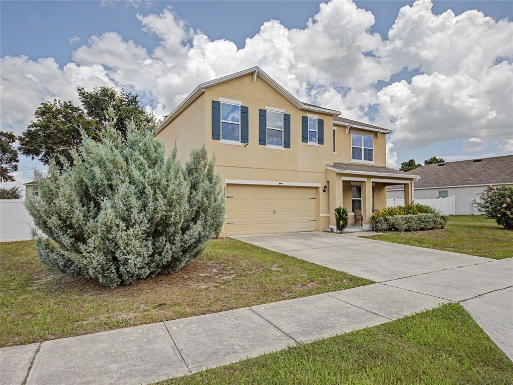 A two-story tan house features a two-car garage, dark shutters, and a front porch — 2942 NE 46TH AVENUE, OCALA, FL
