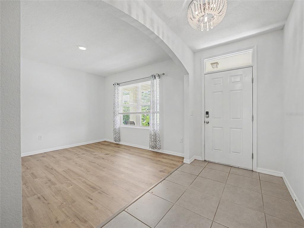 An entryway with tile flooring leads to a living area featuring wood-look floors and windows — 2942 NE 46TH AVENUE, OCALA, FL