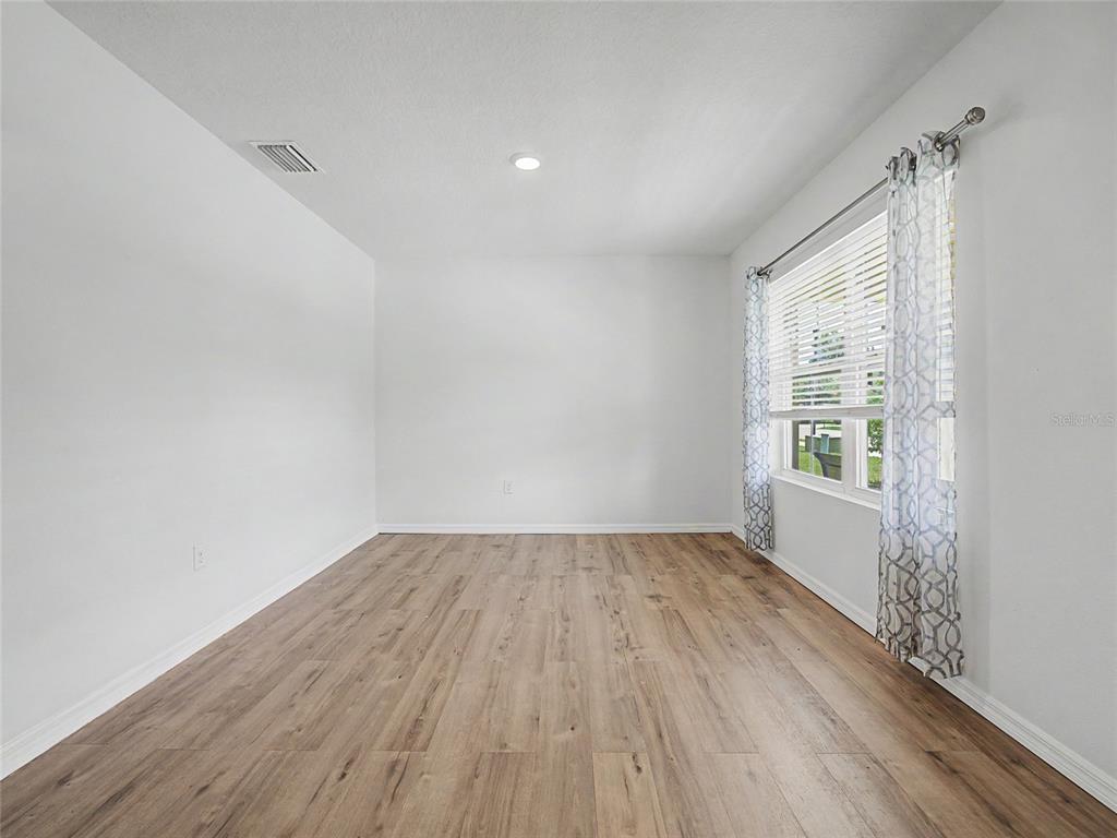An empty room with white walls, light wood-look flooring, and a window with curtains — 2942 NE 46TH AVENUE, OCALA, FL