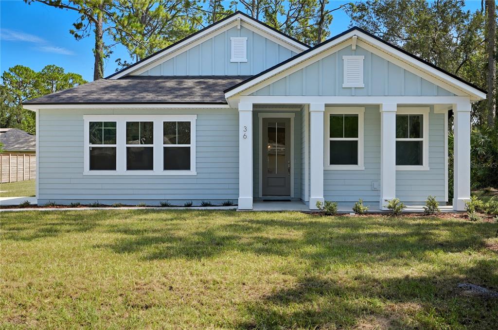 A light blue, single-story house with white trim, a covered porch, and a grassy yard — 36 BROCKTON LANE, PALM COAST, FL