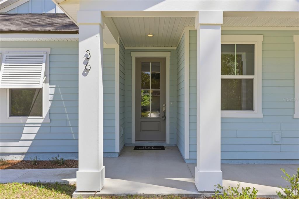 A light blue house exterior features a covered front porch with white columns and pillars — 36 BROCKTON LANE, PALM COAST, FL