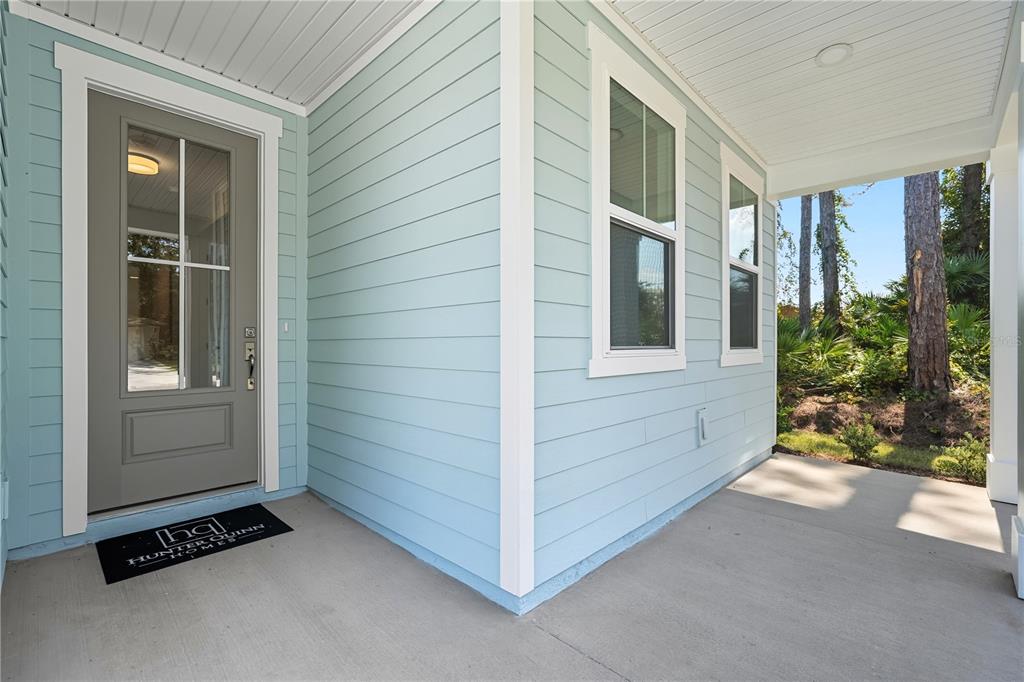 A light blue house exterior features a gray front door and a concrete porch — 36 BROCKTON LANE, PALM COAST, FL
