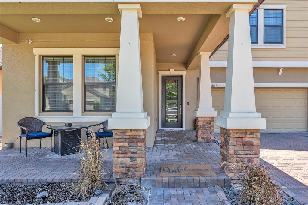 A front porch features stone-based columns, a glass-paneled door, and a small seating area — 13344 ORCA SOUND DRIVE, RIVERVIEW, FL