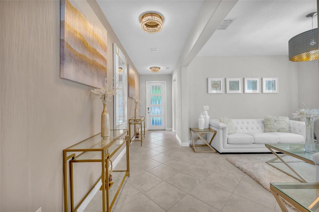 A bright entryway features tile floors, gold console tables, and a view into a living room — 13344 ORCA SOUND DRIVE, RIVERVIEW, FL