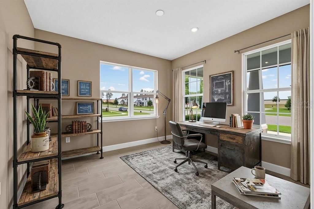 A home office features a desk, industrial-style shelving, a rug, and windows overlooking a neighborhood — 3894 CAPITAL REEF WAY, APOPKA, FL