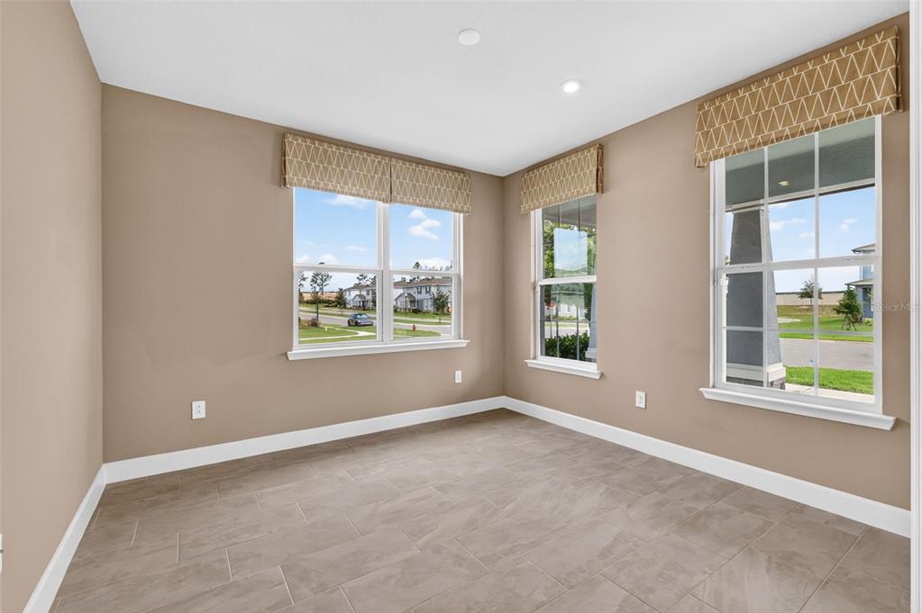 An empty room with tan walls, tile flooring, and three windows featuring patterned valances — 3894 CAPITAL REEF WAY, APOPKA, FL